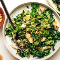 a white plate topped with broccoli salad next to two bowls filled with food