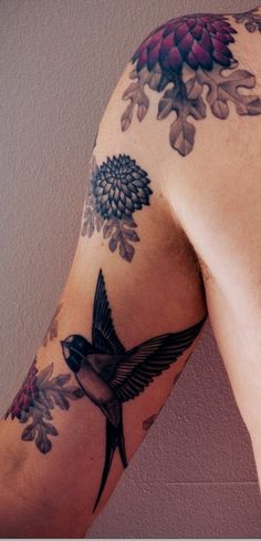 a man with a tattoo on his arm has a flower and bird design on it