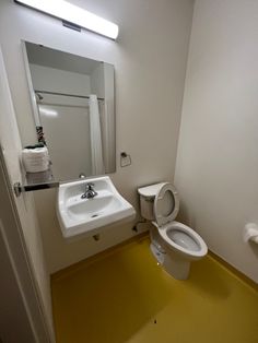 a white toilet sitting next to a sink in a bathroom under a mirror on the wall