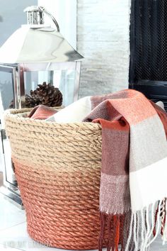 a basket with a blanket on top of it next to a lamp and a fire place