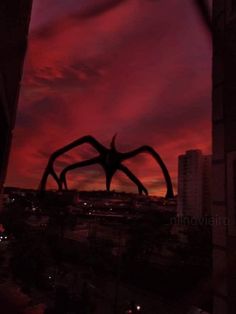 the silhouette of a giant spider in front of a red and purple sky at night