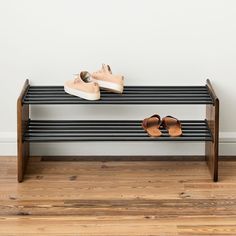 two pairs of shoes are sitting on a bench in front of a white wall and hardwood floor