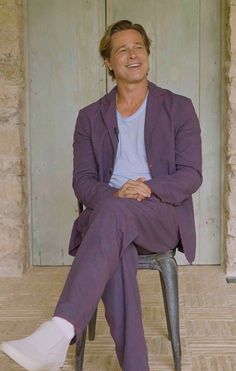 a man sitting on top of a metal chair in front of a door with his legs crossed