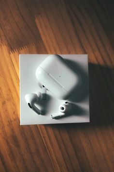 an apple airpods sitting on top of a wooden table next to a charger