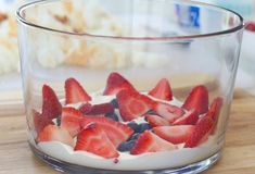 a bowl filled with strawberries and blueberries on top of a wooden table