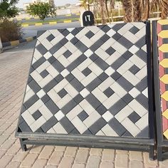 two black and white tiles sitting next to each other on top of a brick sidewalk