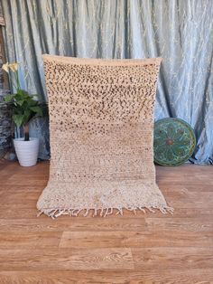 a crocheted blanket sitting on top of a wooden floor next to a potted plant