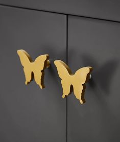 two yellow butterflies hang on the side of a gray cabinet with black doors and handles