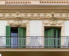 an apartment building with green shutters and balcony