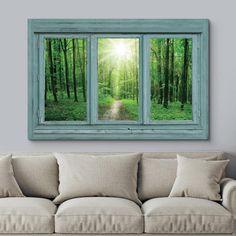 a living room with a couch and two windows that look out to the woods outside