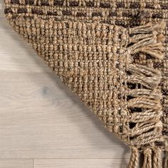 an area rug with fringes on top of white wooden flooring and wood floors