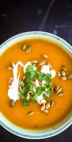 a white bowl filled with carrot soup and topped with sour cream