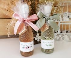 two wine bottles with bows on them sitting next to each other in front of a basket