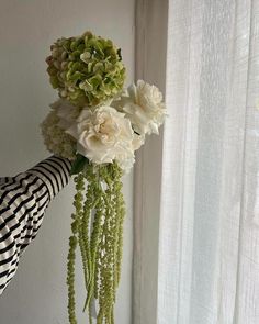 a vase filled with white flowers next to a window