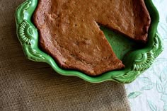 a piece of chocolate cake on a green plate with a slice missing from the pie