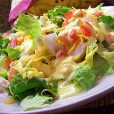 a white plate topped with lettuce and salad next to a pink napkin on top of a table