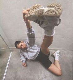 a woman laying on the ground with her feet up and holding onto a sneaker