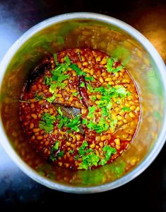 a pot filled with beans and cilantro on top of a table