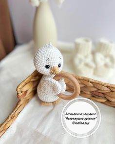 a small crocheted white bird holding a wooden ring