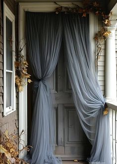 an open door with sheer curtains on the front and side of it, in front of a house