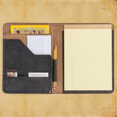 an open notebook with notepad, pen and pencil