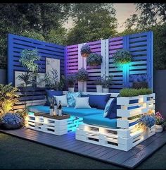 an outdoor seating area is lit up with blue and white lights, surrounded by potted plants