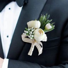 a man in a tuxedo holding a boutonniere with white flowers