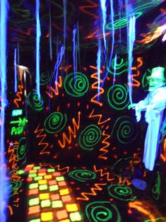 a man standing in front of a wall with neon lights on it's walls