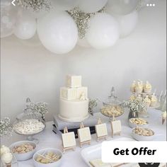 a table topped with lots of desserts and white balloons