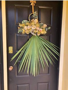 a front door decorated with flowers and palm fronds, hanging from the side