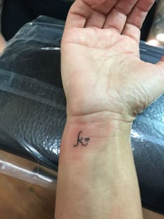 a person's hand with a small tattoo on it and the letter k in cursive writing