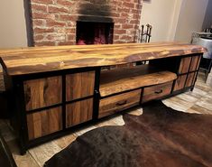 a large wooden table with drawers in front of a fire place and brick wall behind it