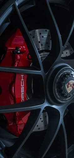 the front wheel of a sports car with red brake pads and black spokes on it