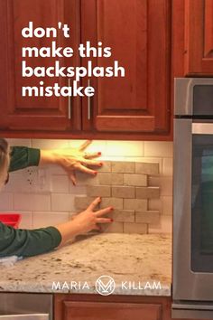 a woman is cleaning the kitchen counter with her hands and reaching for something on the tile