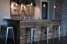 a bar with stools in front of it and lights hanging from the ceiling above