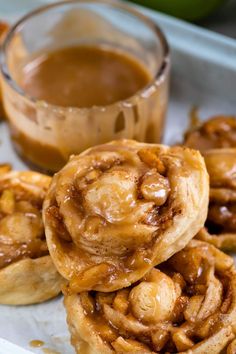 some cinnamon rolls are stacked on top of each other with caramel sauce in the background