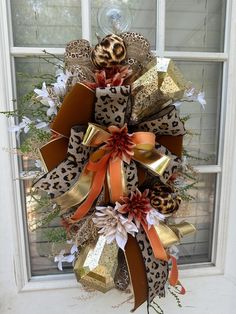 a leopard print wreath with orange and gold bows on the front door, next to a window