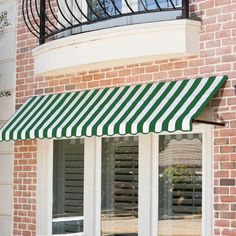 a red and white striped awning on the side of a brick building with french doors