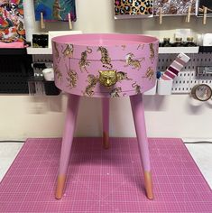 a pink table with gold decorations on the top and legs, sitting in front of a wall