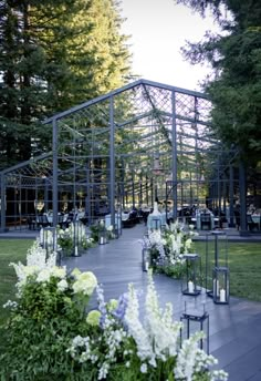 an outdoor dining area with flowers and candles on the table, surrounded by trees in the background