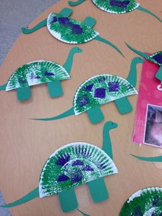 some paper plates with green and blue designs on them are sitting on a wooden table