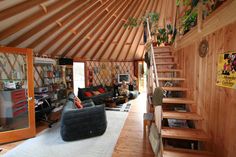 a living room filled with lots of furniture and wooden stairs leading up to a loft