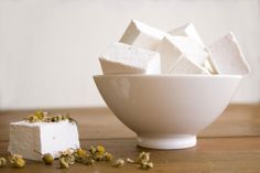 several pieces of marshmallow in a white bowl next to a block of cake