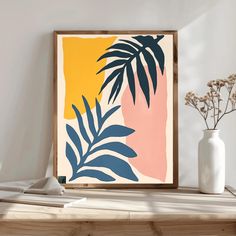 an art print with palm leaves on a shelf next to a white vase and flowers