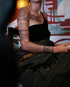 a woman with tattoos on her arm sitting down