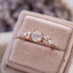 an engagement ring with three stones in it sitting on top of a pink velvet box