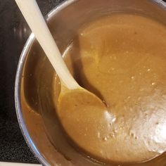 a wooden spoon in a saucepan filled with brown liquid on top of a stove