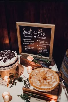 a table topped with cakes and candles next to a sign that says sweet as pie