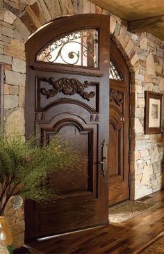 a large wooden door in front of a stone wall and potted plant on the floor