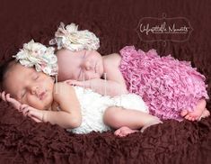 a baby is laying down on a brown blanket with pink flowers in it's hair